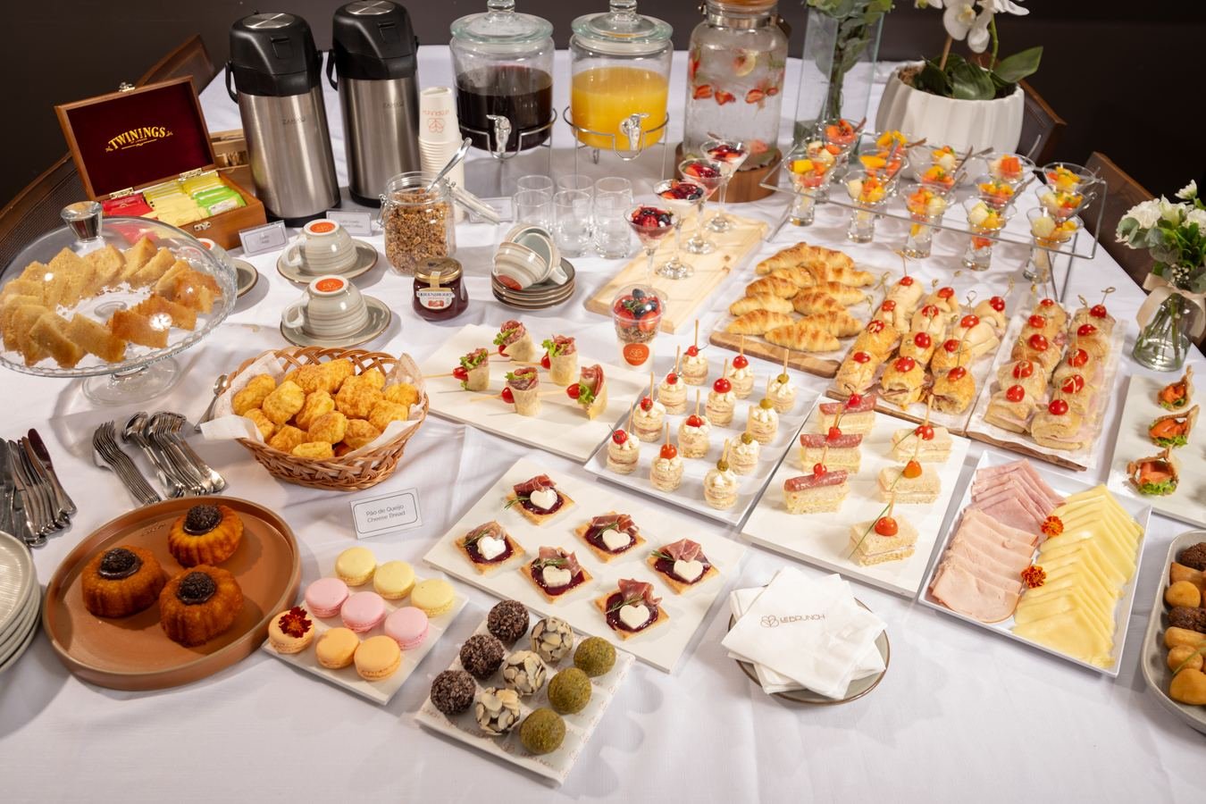 Mesa de café da manhã corporativo montada pelo Le Brunch, com pães, frios, frutas e sucos