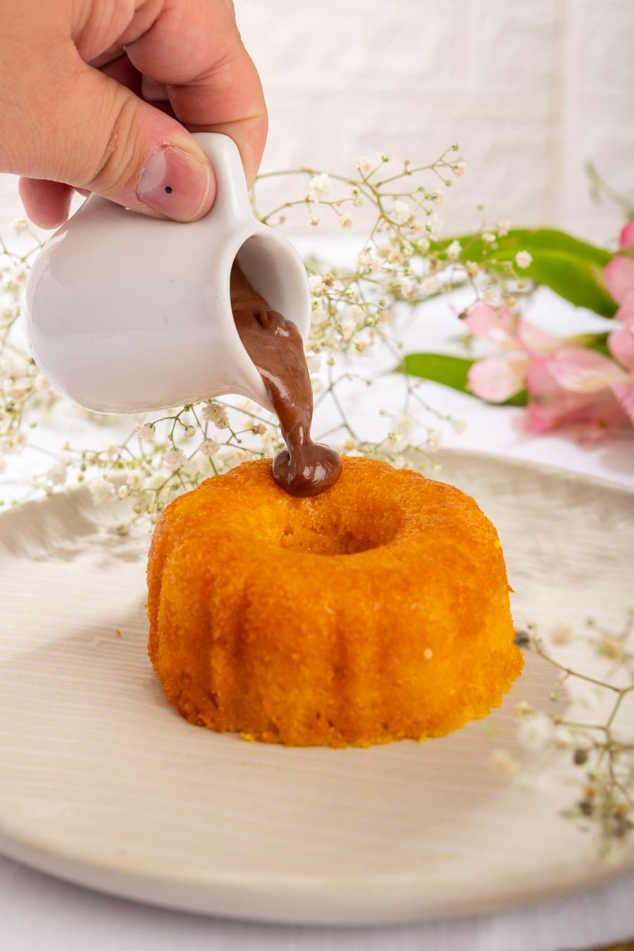 Calda de chocolate sendo servida sobre mini bolo de cenoura